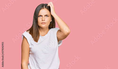 Young caucasian woman wearing casual white tshirt confuse and wonder about question. uncertain with doubt, thinking with hand on head. pensive concept.