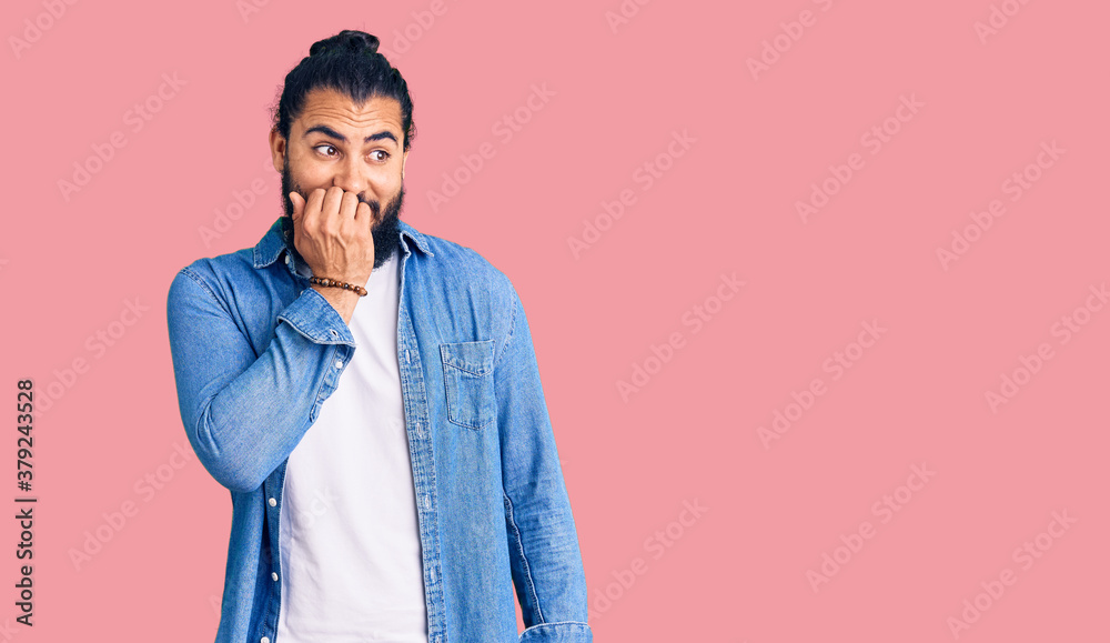 Young arab man wearing casual denim shirt looking stressed and nervous with hands on mouth biting nails. anxiety problem.