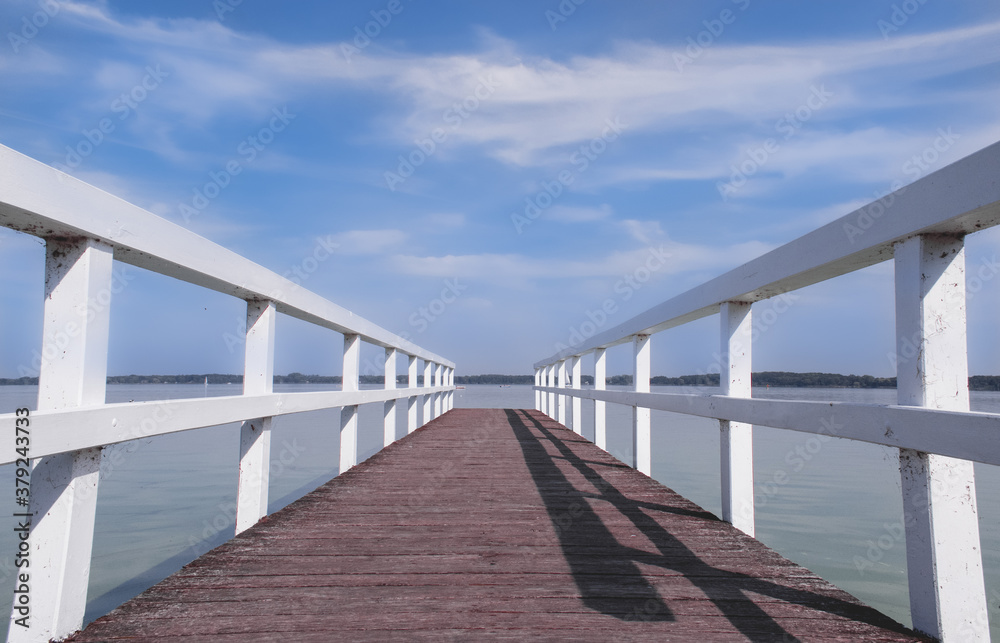 lonely wooden bridge at a calm lake with a cloudy sky lonely wooden bridge at a calm lake with a cloudy sky