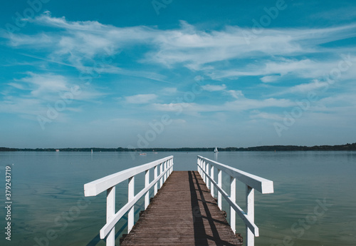lonely wooden bridge at a calm lake with a cloudy sky