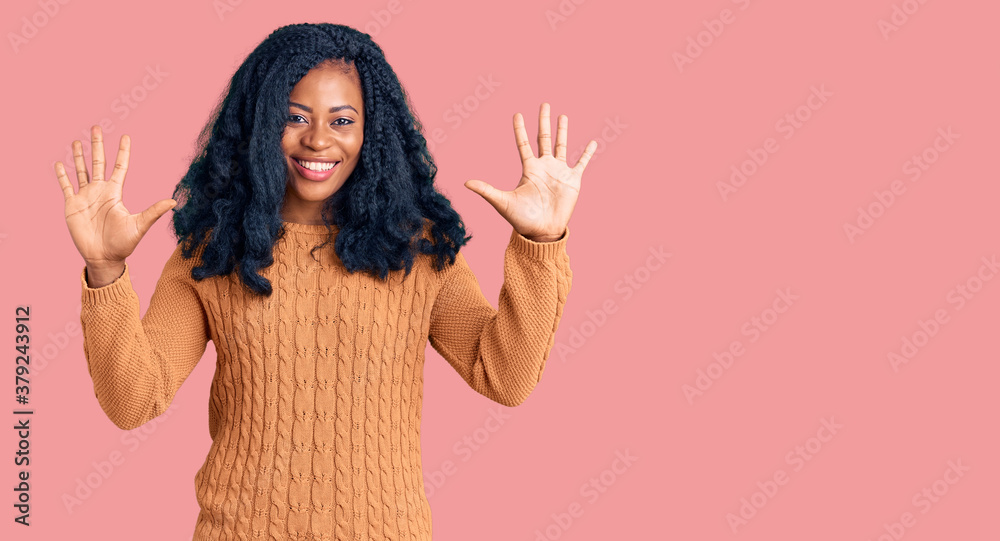 Beautiful african american woman wearing casual sweater showing and pointing up with fingers number ten while smiling confident and happy. Beautiful african american woman wearing casual sweater showing and pointing up with fingers number ten while smiling confident and happy.