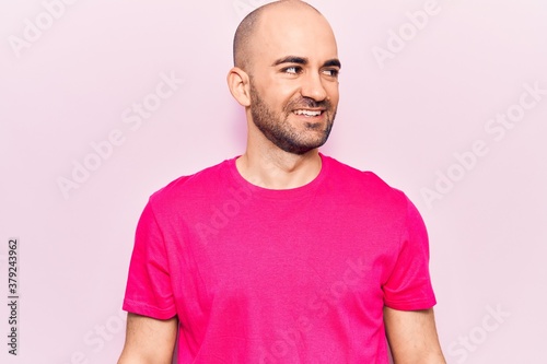 Young handsome bald man wearing casual t shirt looking to side, relax profile pose with natural face and confident smile.