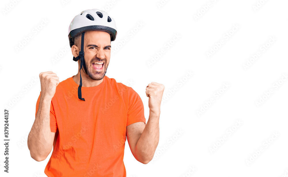 Young handsome man wearing bike helmet screaming proud, celebrating victory and success very excited with raised arms Young handsome man wearing bike helmet screaming proud, celebrating victory and success very excited with raised arms