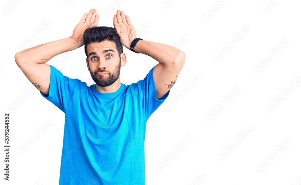 Young handsome man with beard wearing casual t-shirt doing bunny ears gesture with hands palms looking cynical and skeptical. easter rabbit concept.