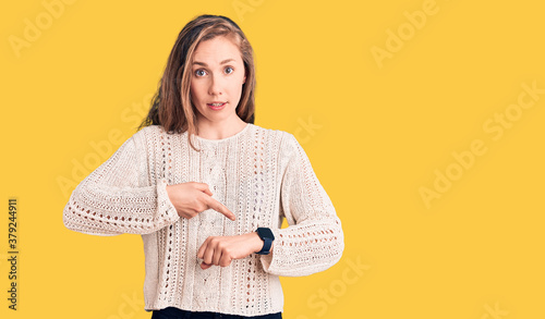 Foto Young beautiful blonde woman wearing casual sweater in hurry pointing to watch t