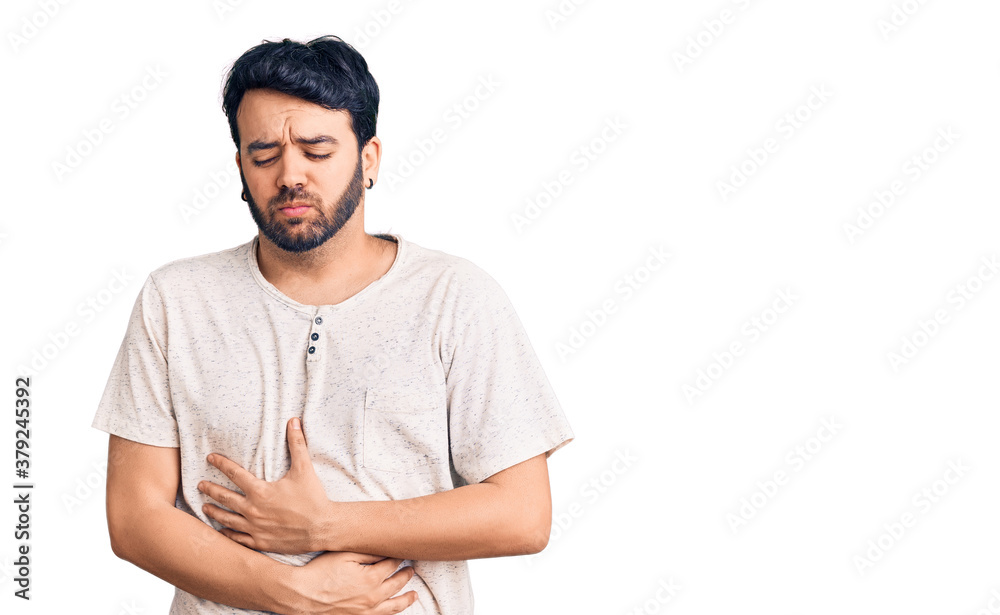 Fototapeta premium Young hispanic man wearing casual clothes with hand on stomach because indigestion, painful illness feeling unwell. ache concept.