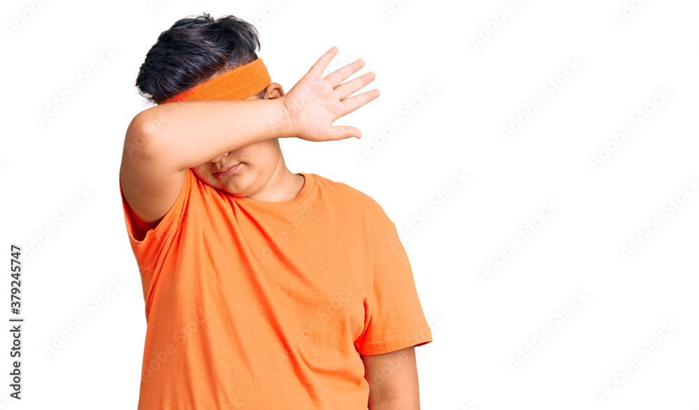 Little boy kid wearing sportswear covering eyes with arm, looking serious and sad. sightless, hiding and rejection concept Little boy kid wearing sportswear covering eyes with arm, looking serious and sad. sightless, hiding and rejection concept