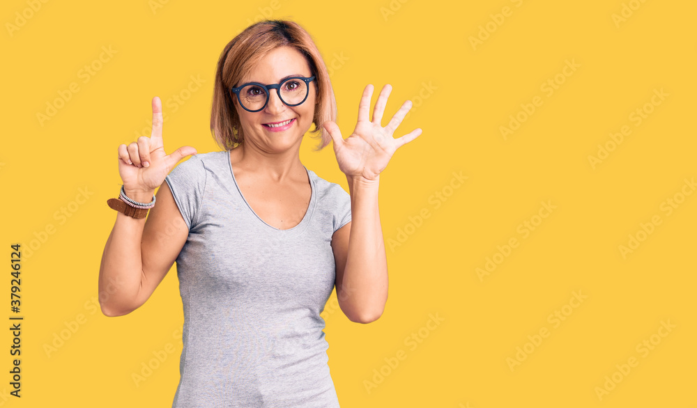 Young blonde woman wearing casual clothes showing and pointing up with fingers number seven while smiling confident and happy. Young blonde woman wearing casual clothes showing and pointing up with fingers number seven while smiling confident and happy.
