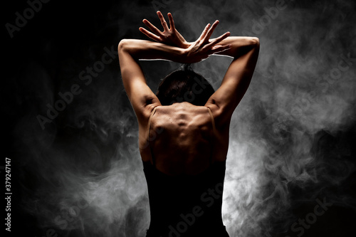 half silhouette modern ballet dancer posing on dark background with smoke