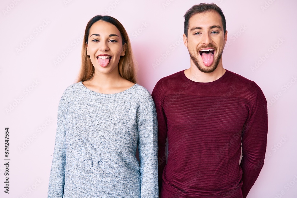 Beautiful couple wearing casual clothes sticking tongue out happy with funny expression. emotion concept. Beautiful couple wearing casual clothes sticking tongue out happy with funny expression. emotion concept.