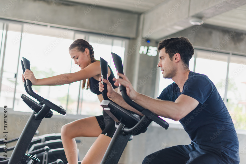Male and female athletes talk about exercise, cycling in the gym. They wear sportswear to exercise. Male and female athletes talk about exercise, cycling in the gym. They wear sportswear to exercise.
