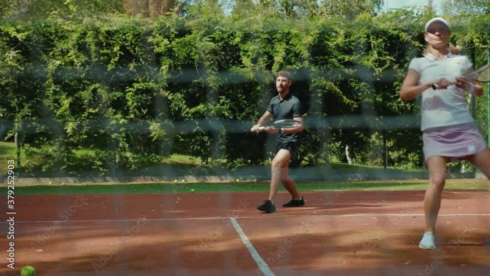 At sunlight woman and man playing tennis on a court competition net athletic active strong play workout match set spare time sport tennis ball slow motion At sunlight woman and man playing tennis on a court competition net athletic active strong play workout match set spare time sport tennis ball slow motion