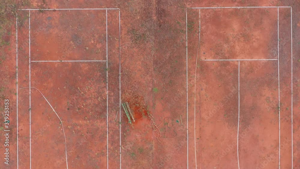 Weeds on a clay tennis court neglected and abandoned. Green grass and