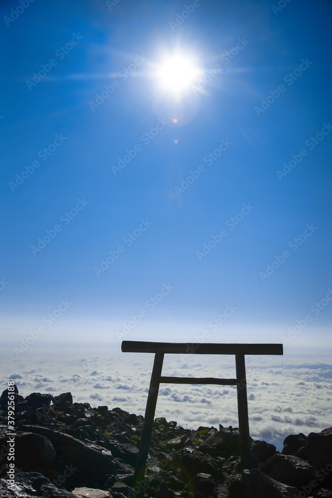 那須の茶臼岳を照らす太陽と、眼下に広がる雲海と鳥居
