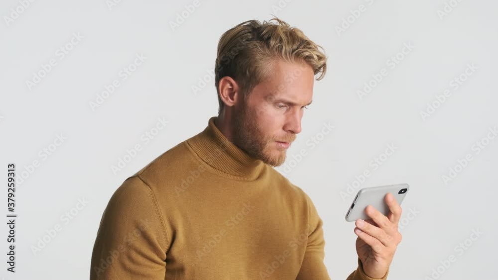 Attractive stylish blond bearded man watching video with interest over white background Attractive stylish blond bearded man watching video with interest over white background