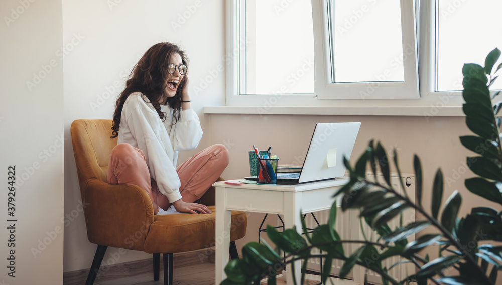 Excited caucasian woman screaming while talking with somebody on laptop and doing homework Excited caucasian woman screaming while talking with somebody on laptop and doing homework
