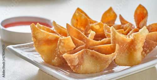 chinese crab rangoon fried wontons on plate with red sauce photo