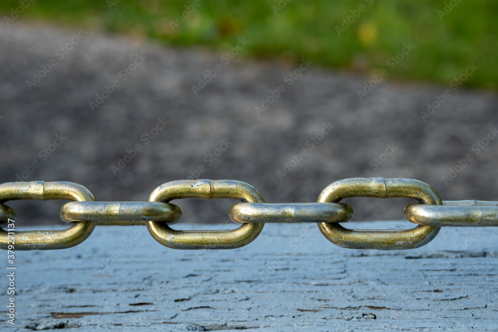 Links of taut steel chain over wood Links of taut steel chain over wood