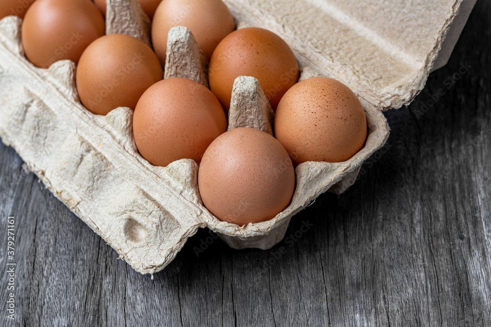 The eggs are packed in brown recycled paper boxes on a wooden table in the kitchen. The eggs are packed in brown recycled paper boxes on a wooden table in the kitchen.