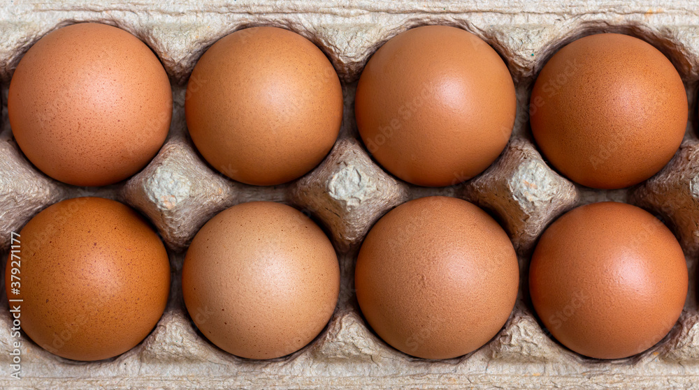 The eggs are packed in brown recycled paper boxes on a wooden table in the kitchen. The eggs are packed in brown recycled paper boxes on a wooden table in the kitchen.