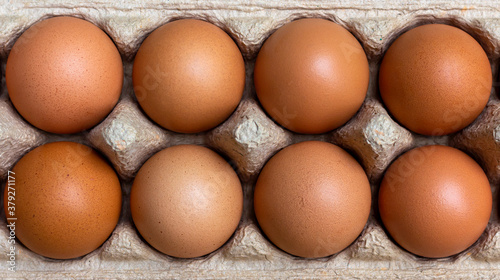 The eggs are packed in brown recycled paper boxes on a wooden table in the kitchen.