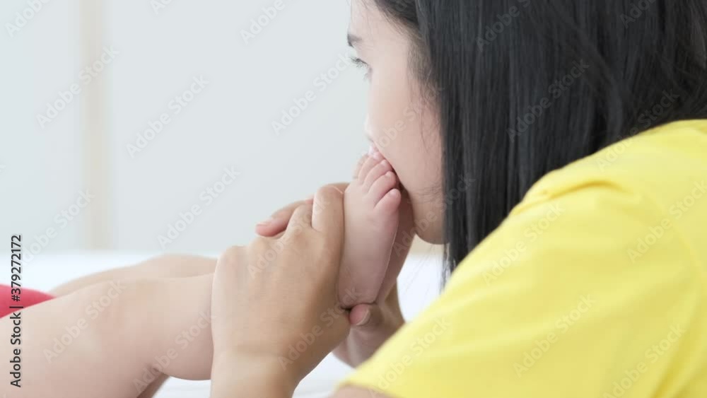 Close up of asian mother kissing her newborn baby's feet in the morning. Close up of asian mother kissing her newborn baby's feet in the morning.