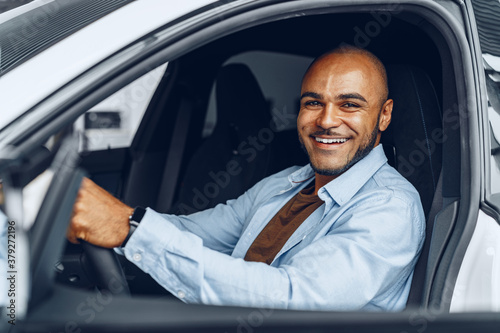 Portrait of a handsome happy African American man sitting in his newly bought car © fotofabrika