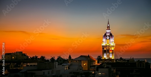 Wonderful panoramic view after sunset over Cartagena with illuminated Cartagena Cathedral against orange-yellow sky
