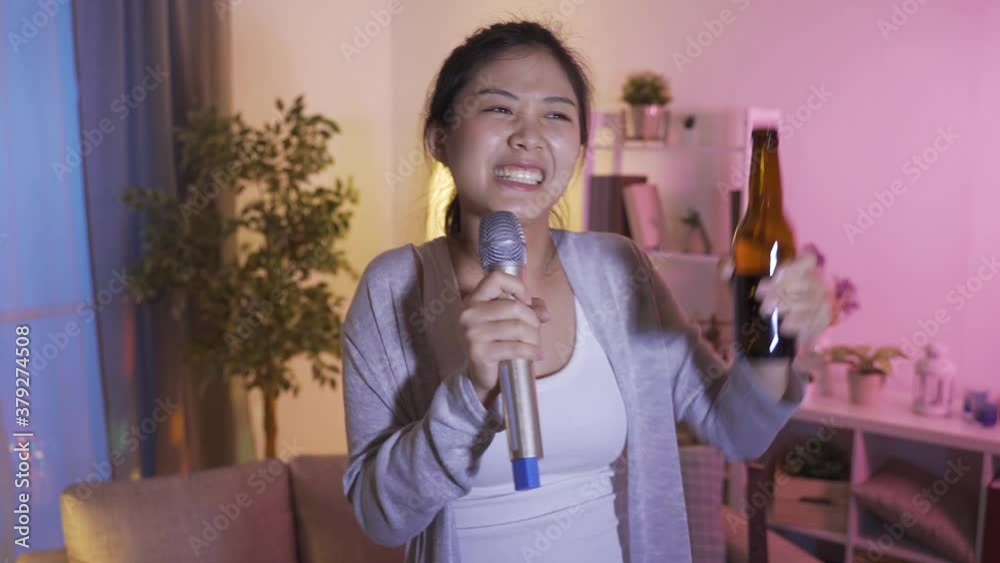 portrait japanese young female singing to microphone and holding beer bottle up in high spirit at home portrait japanese young female singing to microphone and holding beer bottle up in high spirit at home