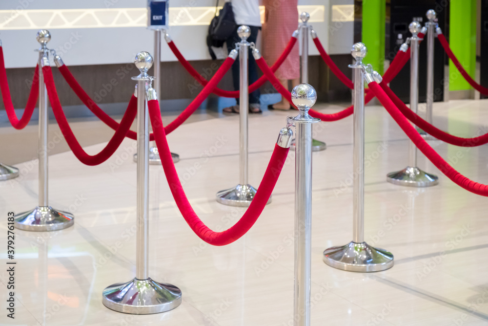 Naklejka premium Fence stainless barricade with red rope blurred interior background.