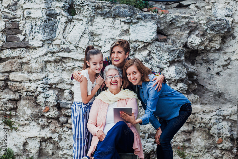 hispanic granddaughters and grandmother watching something on the tablet