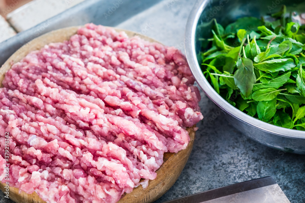 Raw minced meat on the cutting board with fresh herbs.