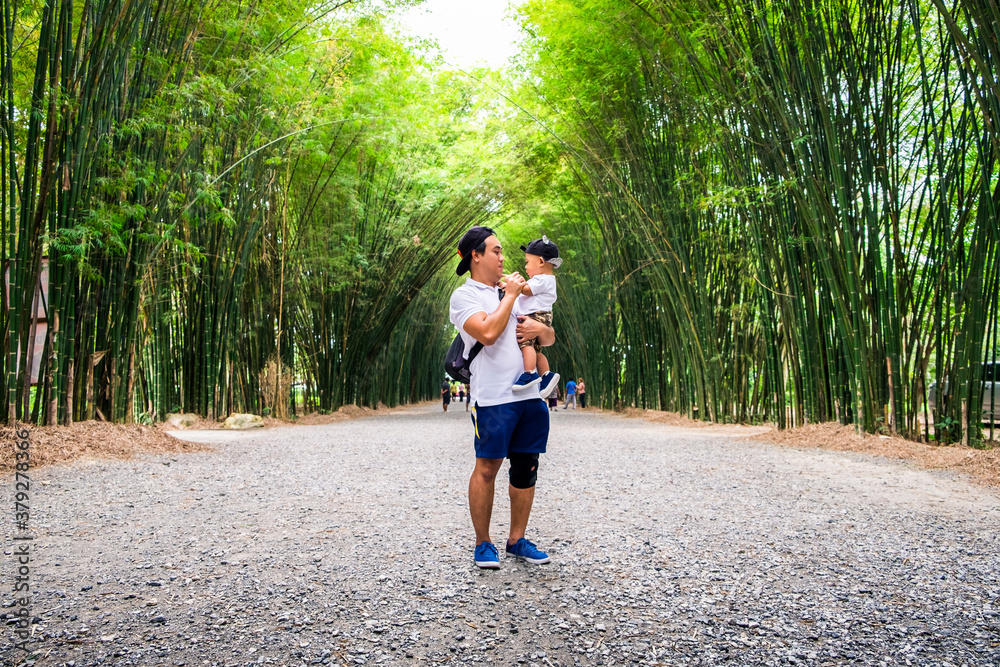 Father and son having good time outdoors at bamboo forest at Thailand. Concept of friendly family and summer vacation. Father and son having good time outdoors at bamboo forest at Thailand. Concept of friendly family and summer vacation.