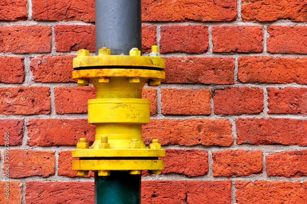 Yellow gutter downpipe and red brick wall as urban background. Yellow gutter downpipe and red brick wall as urban background.