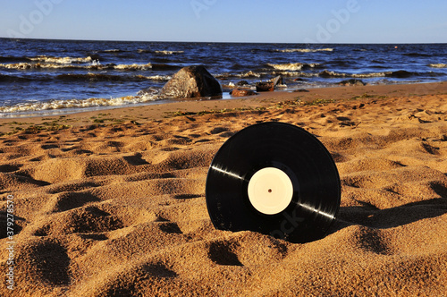 Vinyl record disk on a sandy beach.The background of the sea