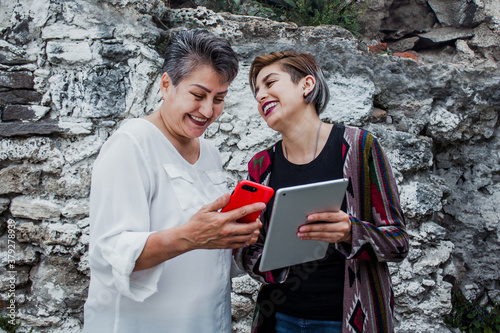 mature Mexican Mother and adult daughter using mobile phone and tablet in Mexico © Marcos