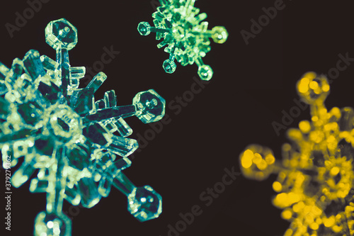 The snowflakes in yellow  blue  turquoise  and green color  align randomly in the dark background.