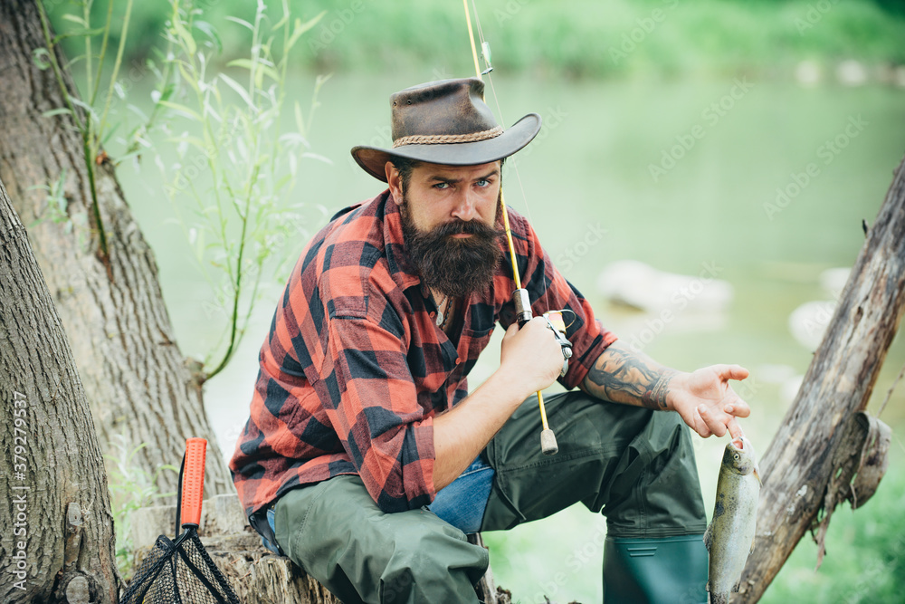 Man fishing relaxing while enjoying hobby. Male hobby. Home of hobbies. Fly fishing adventures. Cheerful mature fisherman fishing in a river outdoors. Bearded elegant man. Angler catching the fish.