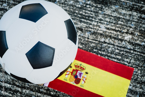 Classic leather soccer ball on the ground with Spain national team flag of the participating country in the championship tournament. 