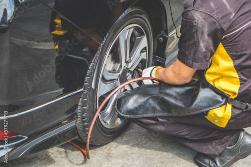 Cropped shot of mechanic pumping up car tire. Inflating the tyre.
