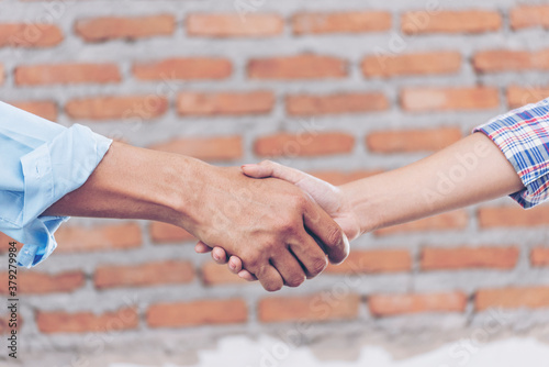 Civil Construction engineer teams shaking hands together wear work helmets worker on construction site. Foreman industry project working engineer teamwork. Two asian engineer team shake hands together