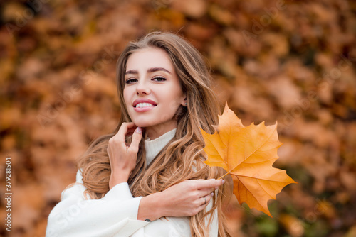 Happy autumn woman having fun with leaves outdoor in park.