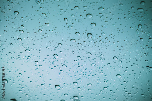 Blue drops of rain on a window glass in the city. Image of raindrops texture background.