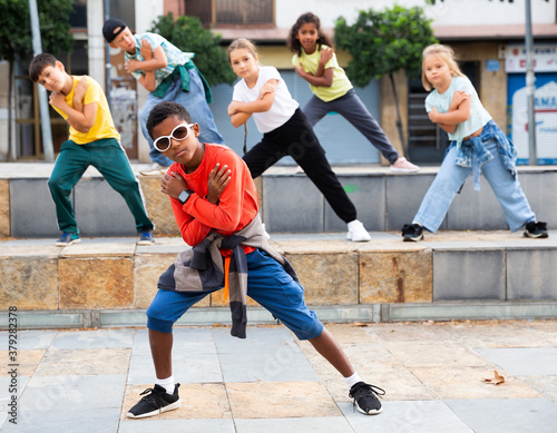 Little boy hip hop dancer exercising with friends at open air dance class photo