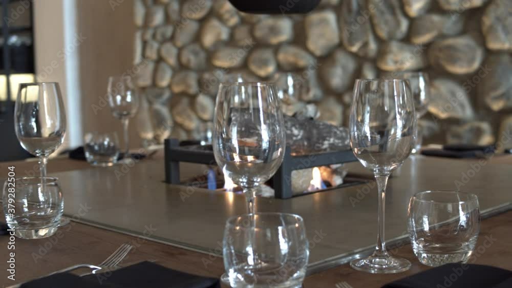Floating shot around around a set table in a restaurant with central fire pit.