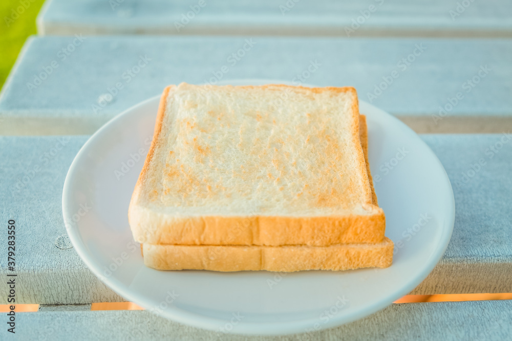 Toast bread in white plate on wooden table.