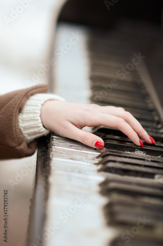 Close-up of a manicured hand playing the piano. Red varnish