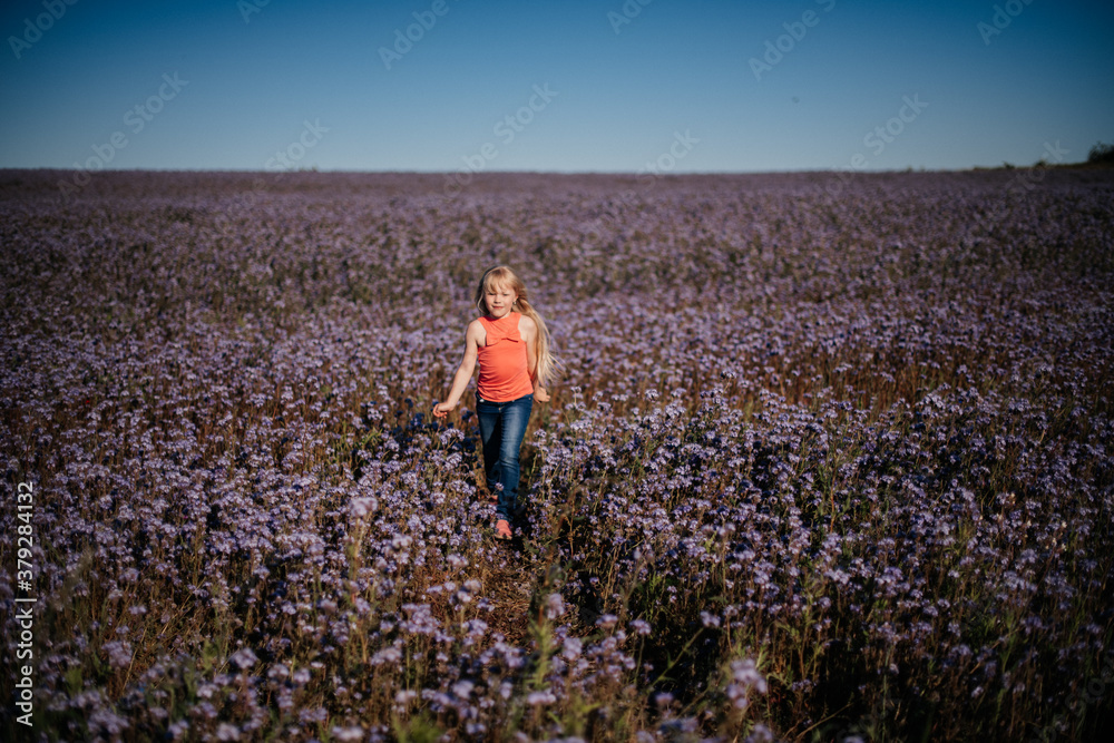 Obraz premium Portrait of a happy girl in a purple field of flowers. Reuniting with nature. Childhood, lifestyle. 