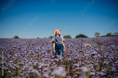 Fototapeta Naklejka Na Ścianę i Meble -  happy child, blond girl runs and jumps in violet flower field. Reconnection with nature.