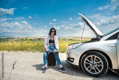 Young woman waiting for help near damaged car.